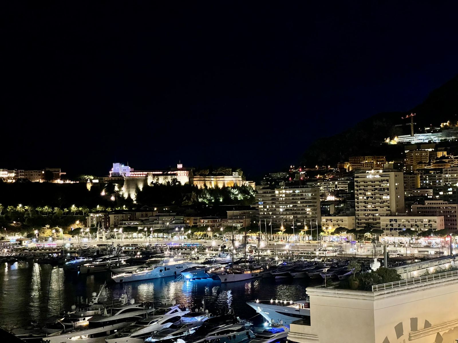 Monaco at night — the harbour lit up, the Prince's Palace glowing on the rock, yachts reflected in the water